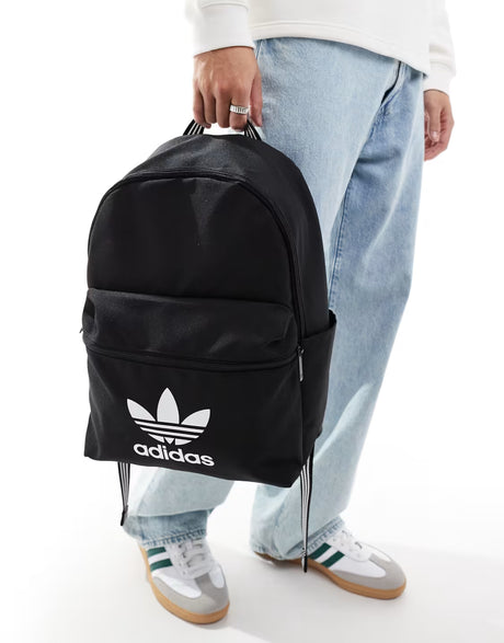 Person holding a black Adidas backpack with a white background